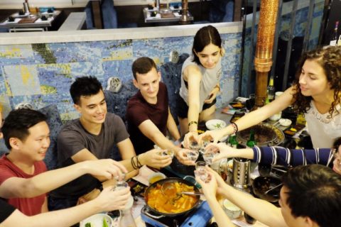 Large of group of people sitting around a table, toasting.