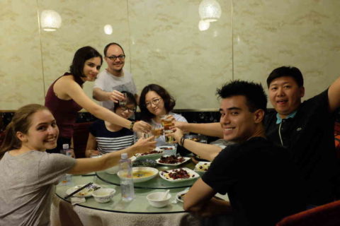 Group of LTL students and staff toasting at a dinner table