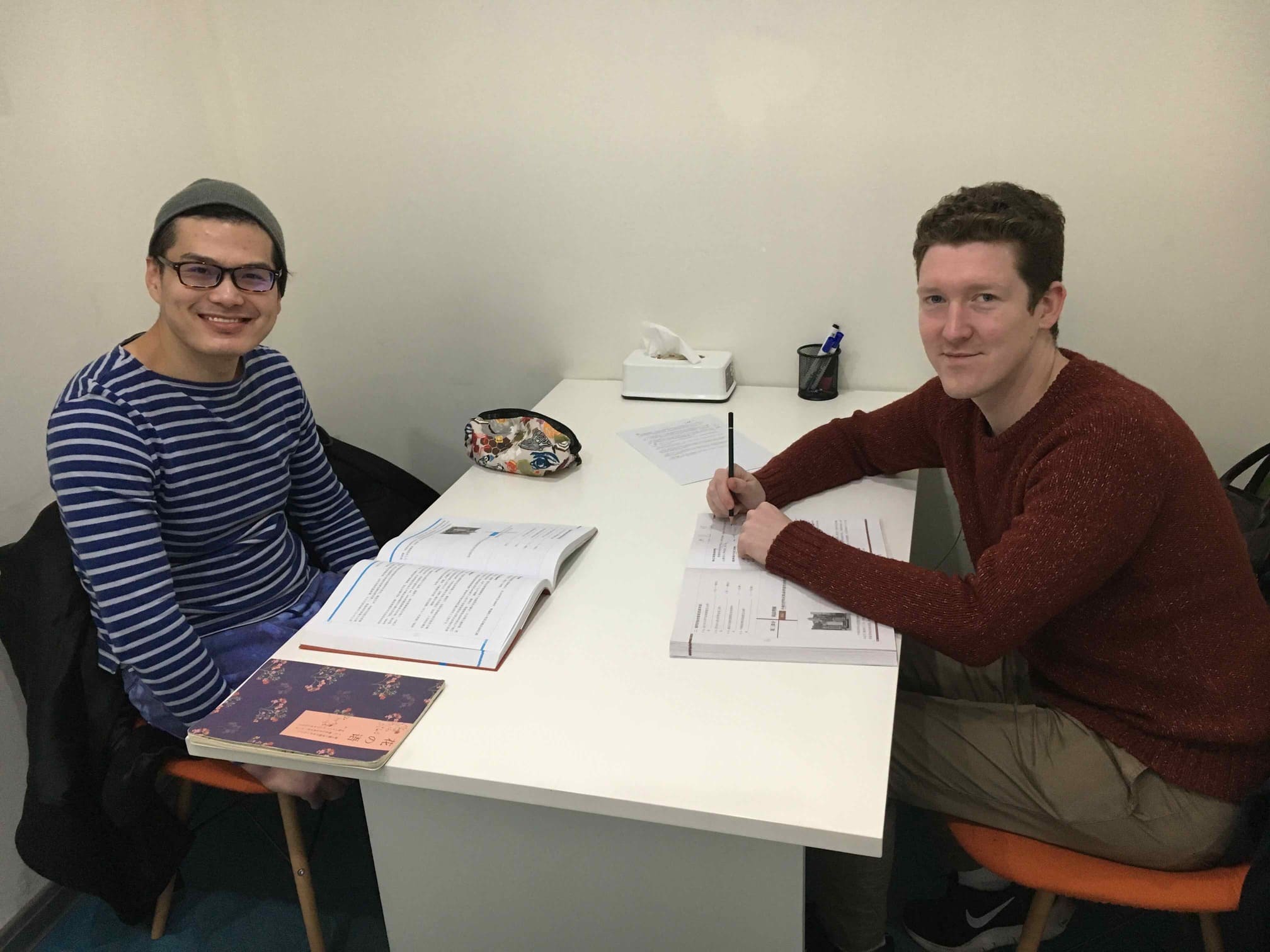 Two students sitting at a desk with books in front of them