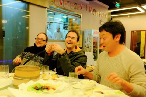 Three men sitting around a dinner table laughing